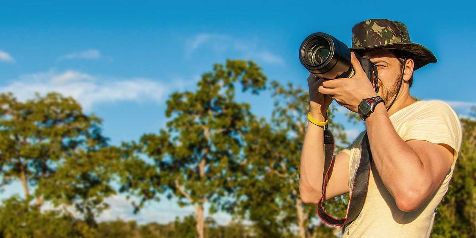 Mann mit Kamera und Safarihut macht Foto