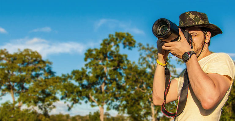 Mann beim Fotografieren mit Safarihut