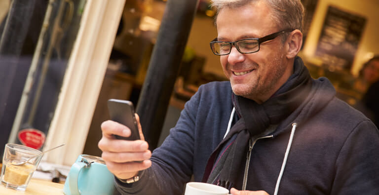 Mann bedient glücklich ein Smartphone