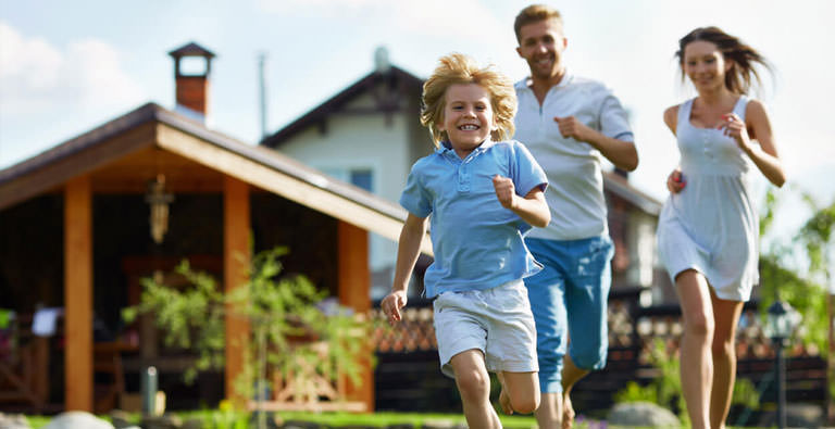 Familie läuft glücklich vor ihrem Haus herum