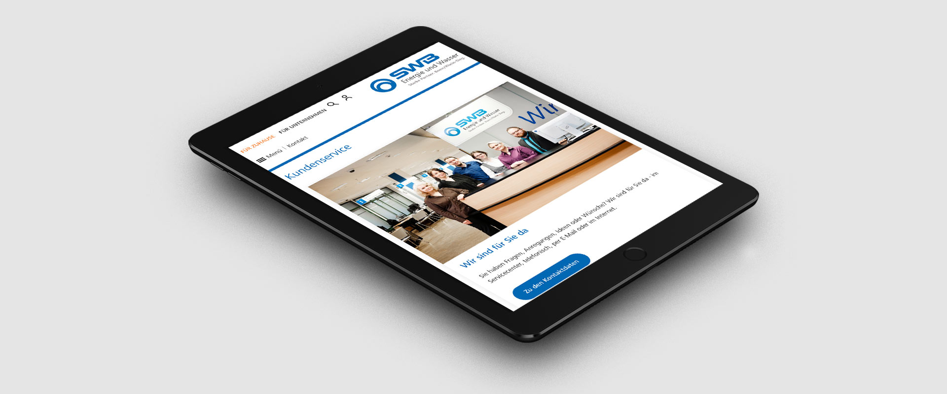 Ein Tablet zeigt eine Website mit einer Gruppe von Personen, die hinter einem Kundendienstschalter stehen.