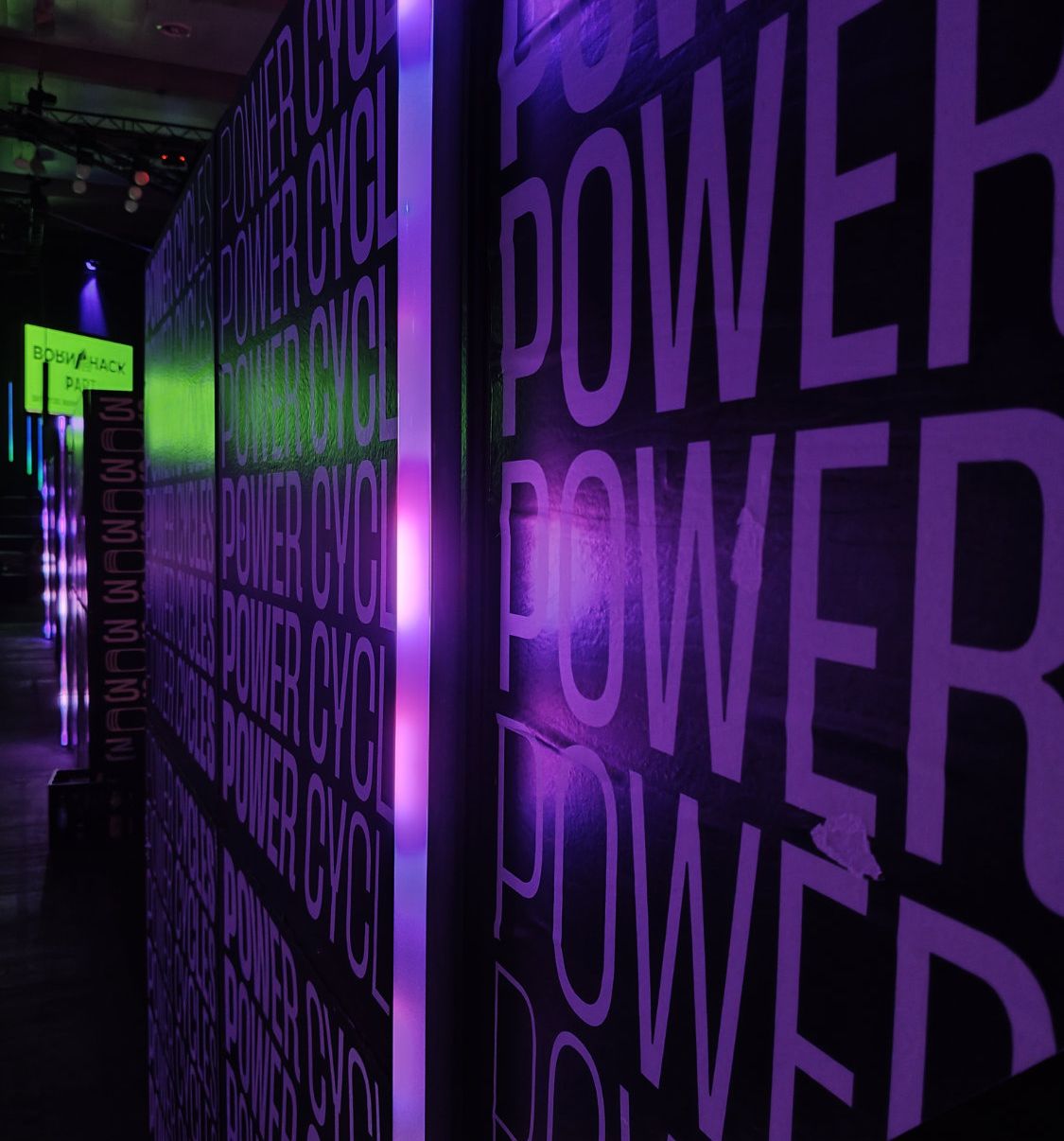 Nahaufnahme einer lila beleuchtenden Wand im Congress Center, auf dem ganz oft "Powercycles" steht