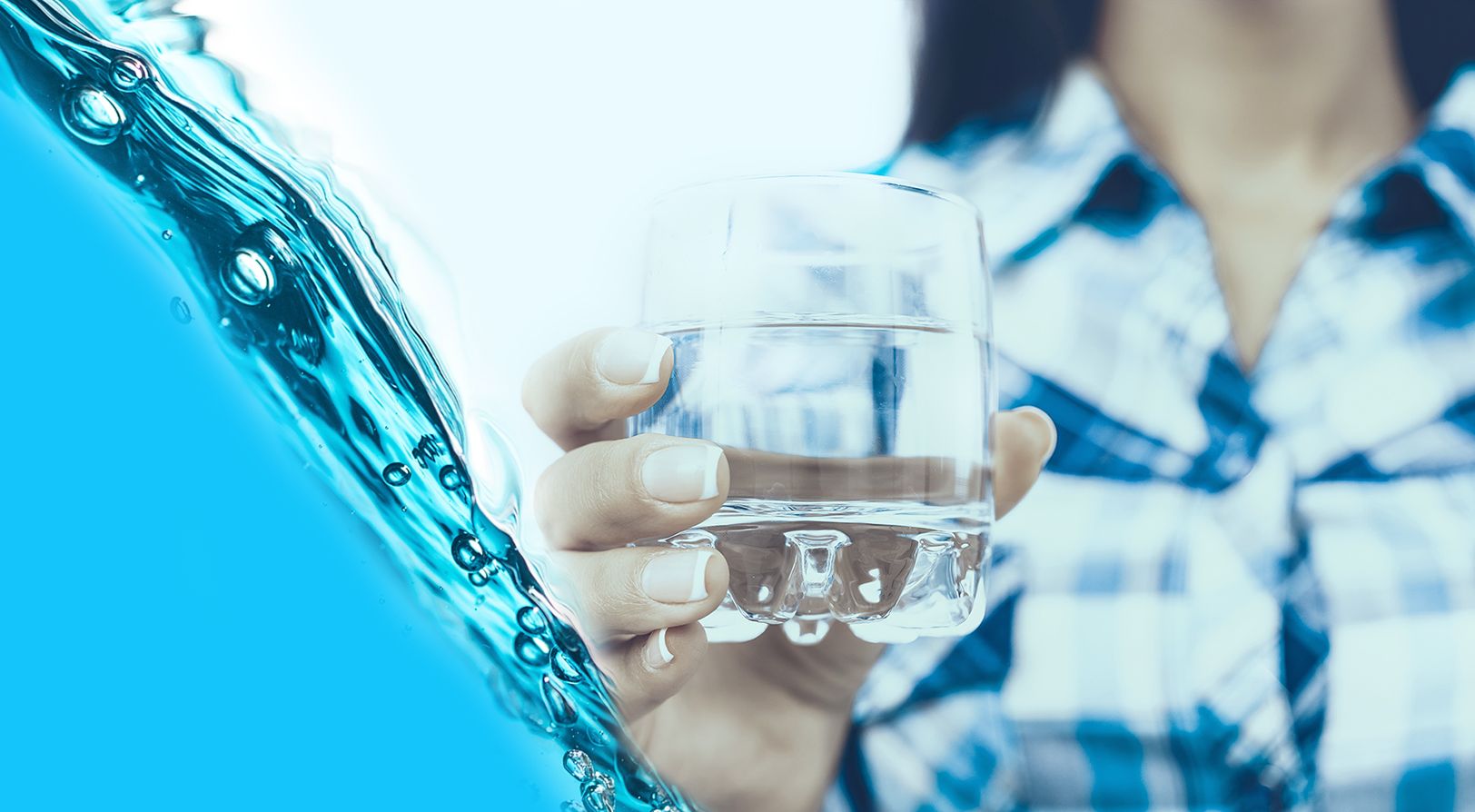 Person in einem blau karierten Hemd, die ein klares Glas Wasser vor einem weißen Hintergrund hält.