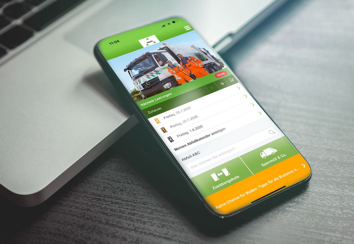 Smartphone auf einem Laptop, das eine Recycling-App mit einem Zeitplan für die Müllabfuhr und ein Foto von Müllmännern zeigt.